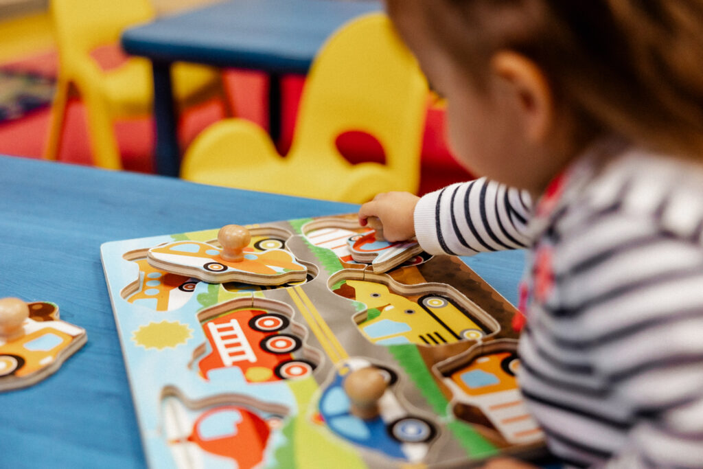 Little girl playing with wooden puzzle