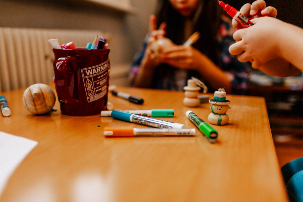 Boy and girl decorating some Christmas ornaments with colorful markers