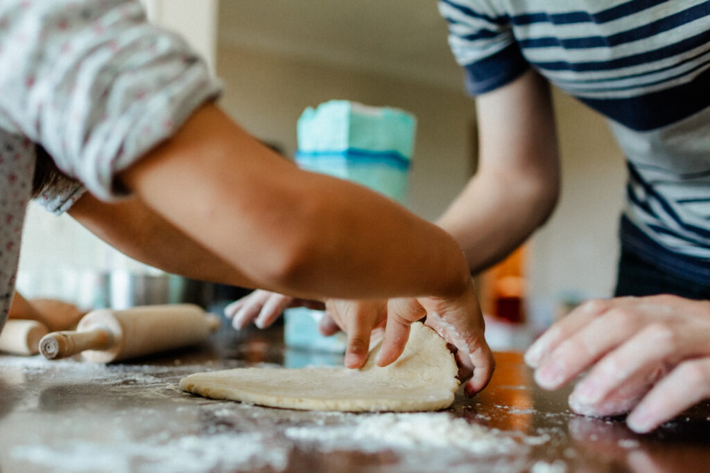 Hands of a girl and her dad preparing cookie dough