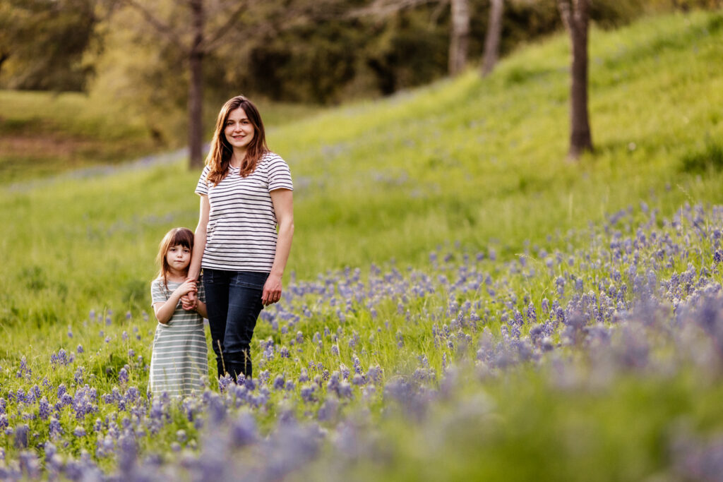 Mother and daughter standing in a bluebonnet field during an evening bluebonnet mini session in Houston