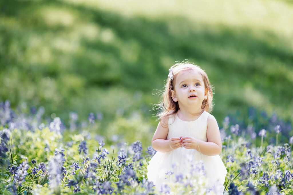 Little girl playing in a bluebonnet field during a spring photo session in Houston