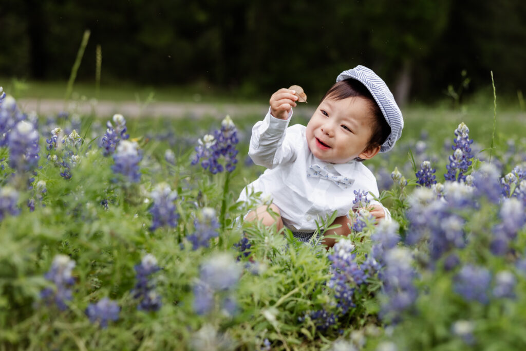 Little boy holding a leave surrounded by bluebonnets in Houston